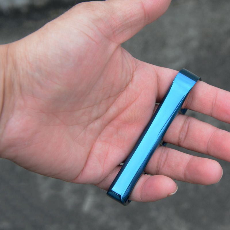 Blue finished steel knuckle lying across an open palm showing its slim side profile