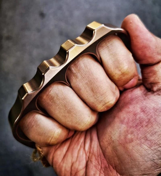 Fist wearing the steel knuckle with the scalloped top rail sitting across the knuckles