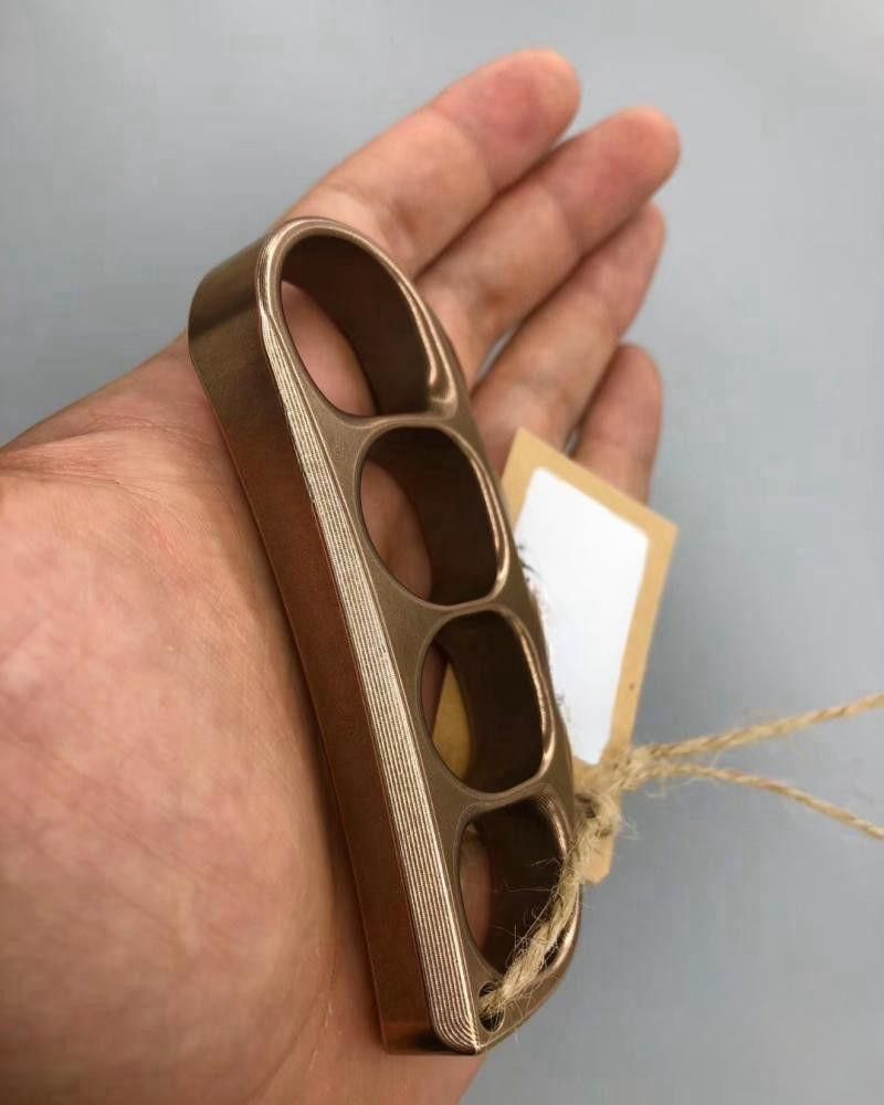 Bronze toned steel knuckle resting on an open palm showing the chamfered side edge and machining lines