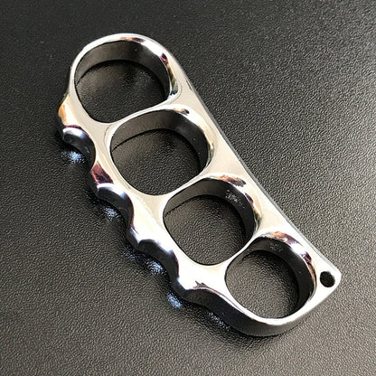 Bright polished steel knuckle lying flat on a dark textured surface with its lanyard hole at the end