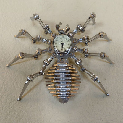 Mechanical spider sculpture with cream clock face and stacked steel abdomen viewed from above on a light leather surface