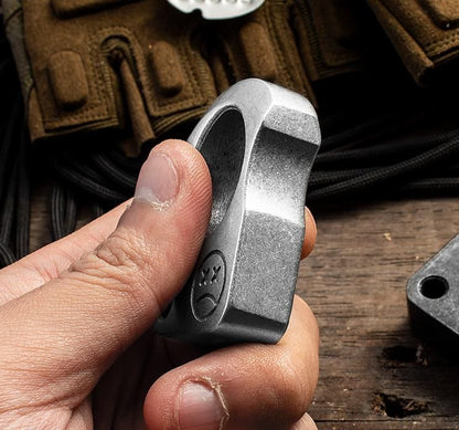 Metal storage tin set with a silver-tone knuckle weight and camo cord in black foam, the engraved lid resting beside it