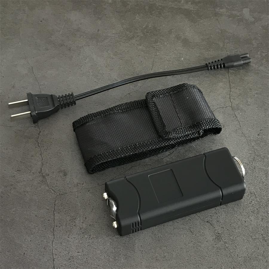 Black 801C stun gun lying on a gray surface showing the light reflector and electrode tips