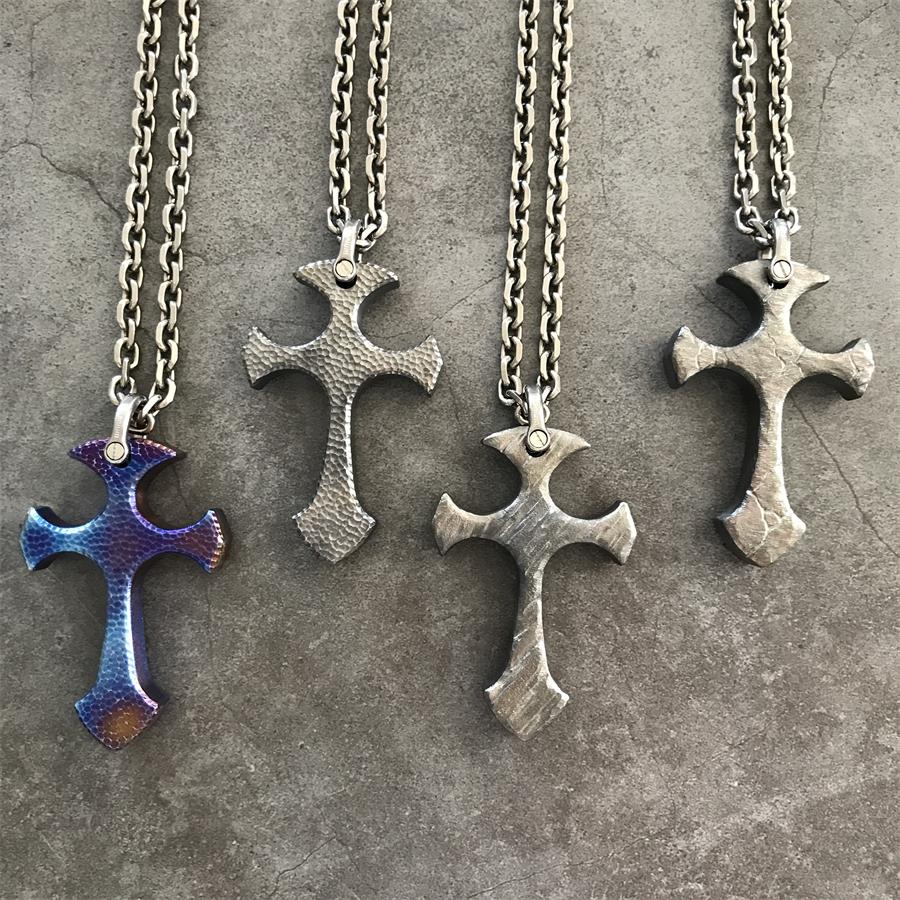 Blaze, Titan, Relic and Obsidian TC21 titanium cross pendants arranged on dark stone surface