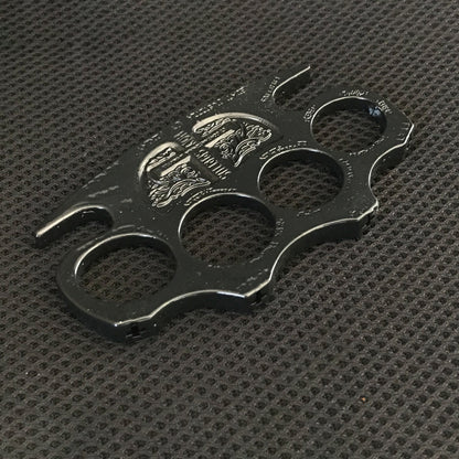 Black knuckle duster lying on a dark textured mat with the shield emblem catching the light