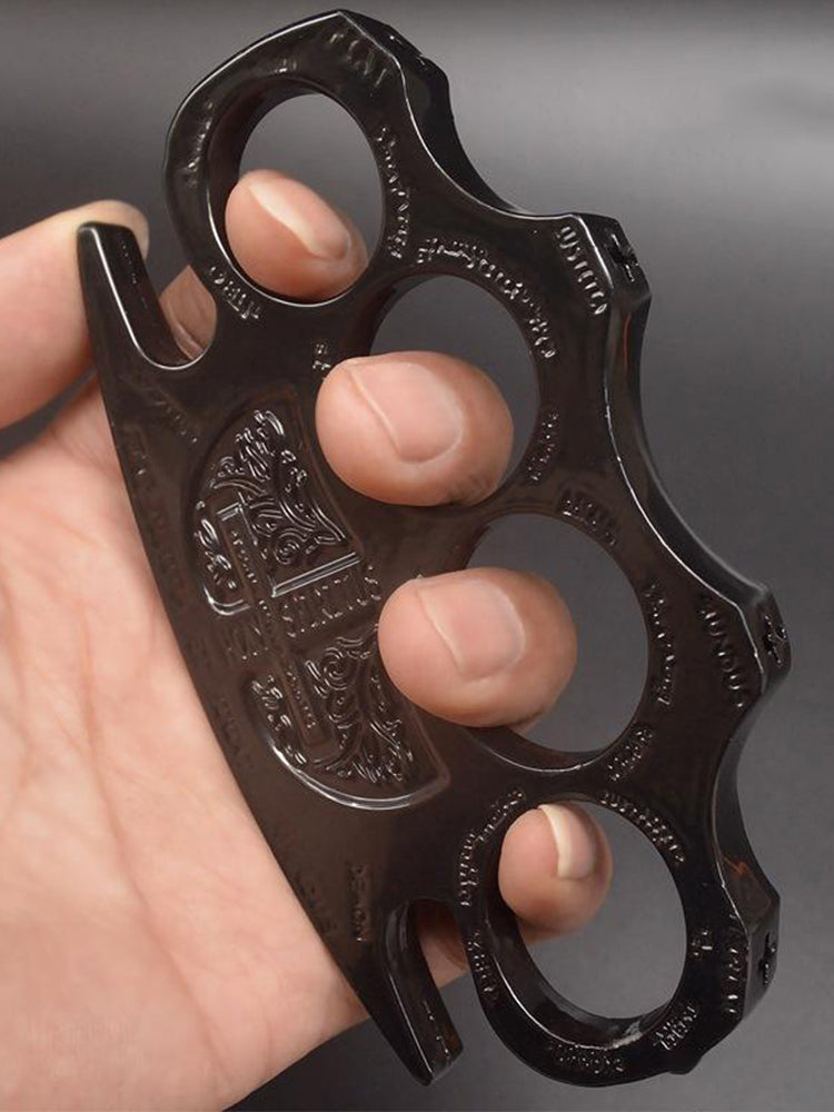 Black knuckle duster worn on the fingers showing the engraved face and frame thickness