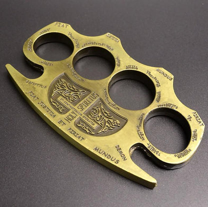 Golden knuckle duster shown at full length with the four stepped finger holes and engraved shield frame on display