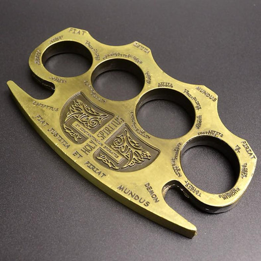 Golden knuckle duster shown at full length with the four stepped finger holes and engraved shield frame on display