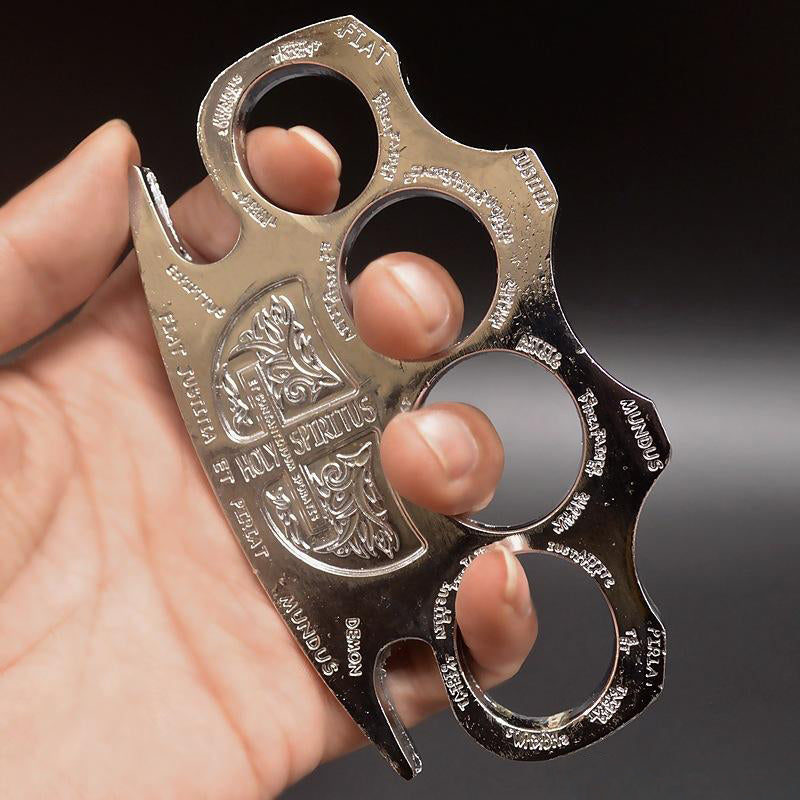 Silver knuckle duster held in a hand with fingers through the holes showing the engraved shield
