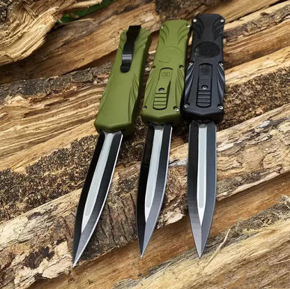 Three automatic OTF pocket knives in green and black handles arranged on weathered wood