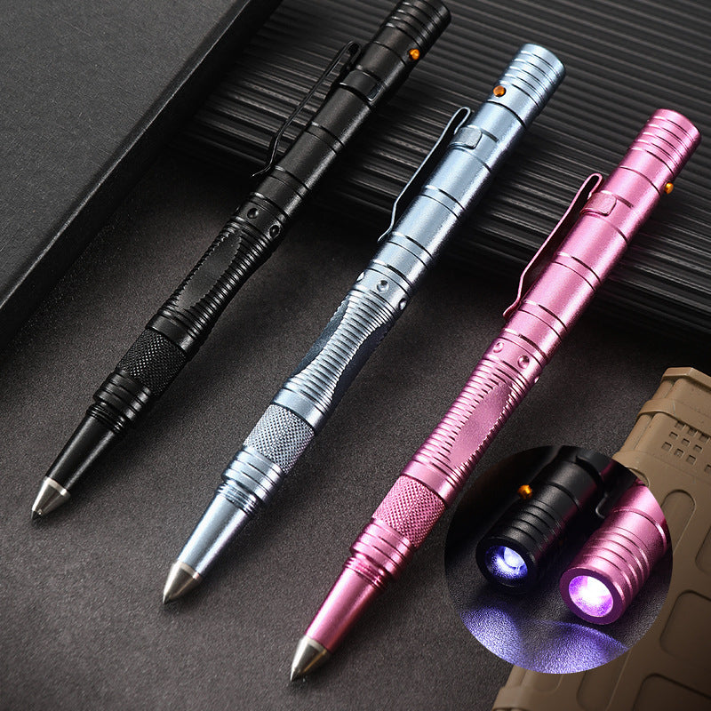 Three aluminum tactical pens in black, silver and pink laid diagonally on a dark ribbed surface, each with a pocket clip, knurled grip band, pointed cone tip and a small button near the top, plus an inset showing two pen heads lit with a purple LED glow.