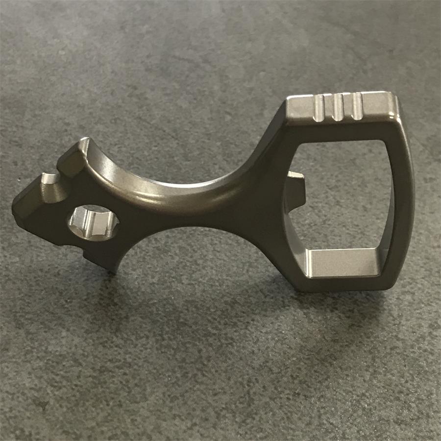 Side profile of the titanium opener tool standing on its loop end with a bit seated in the socket