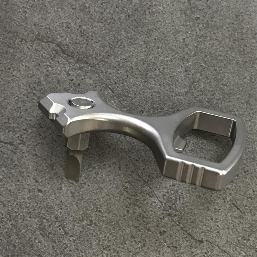 Titanium opener tool on stone with a bit seated in the hex socket and the finger loop to the right
