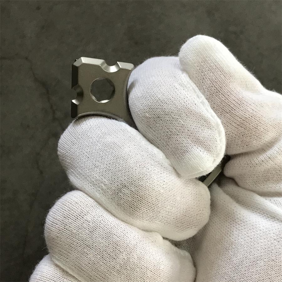 White gloved hand gripping the tapered head of the titanium opener tool