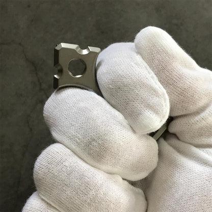 White gloved hand gripping the tapered head of the titanium opener tool