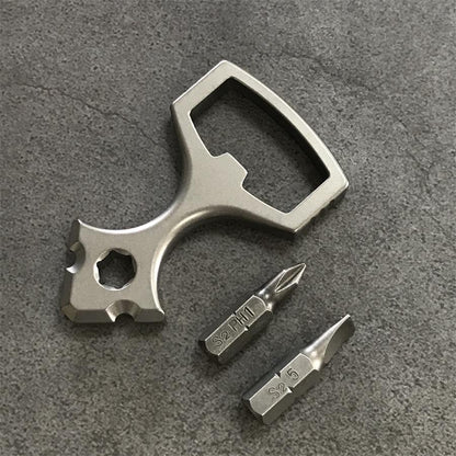 Titanium opener tool beside two screwdriver bits marked S2 on a grey textured surface