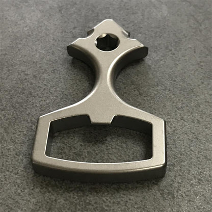 Top-down view of the titanium opener tool with its arrowhead socket end and wide finger loop