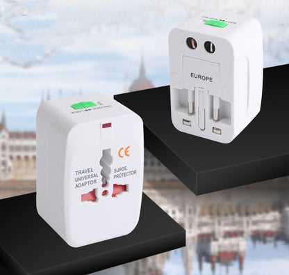 Two universal travel adapters on black display stands against a blurred European cityscape, the socket face and the EUROPE plug side facing outward