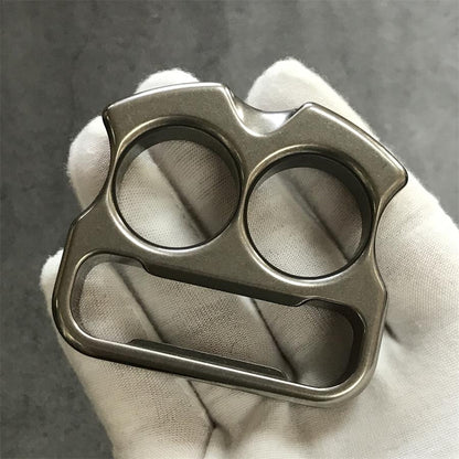 Two-finger titanium duster angled on grey slate with twin-peak top edge up