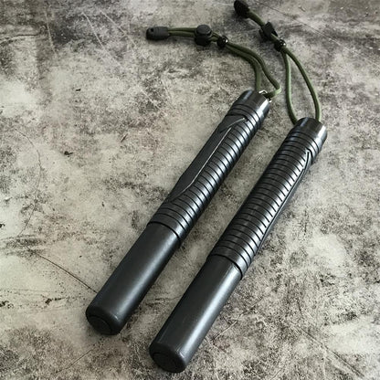 Two collapsed batons side by side on concrete, each with a green cord