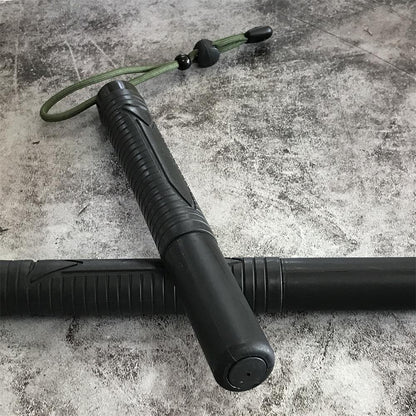 Two black batons crossed on concrete, one showing the capped front end