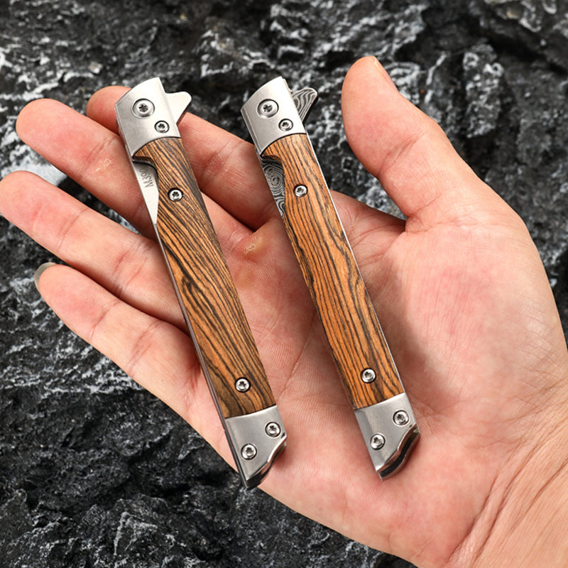 Two closed folding knives resting on an open palm, one showing a Damascus-pattern blade in the fold and the other plain stainless, both with striped wood handles