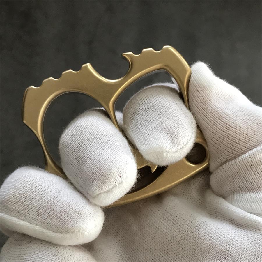 Two fingers worn through brass knuckle holes showing serrated top edge