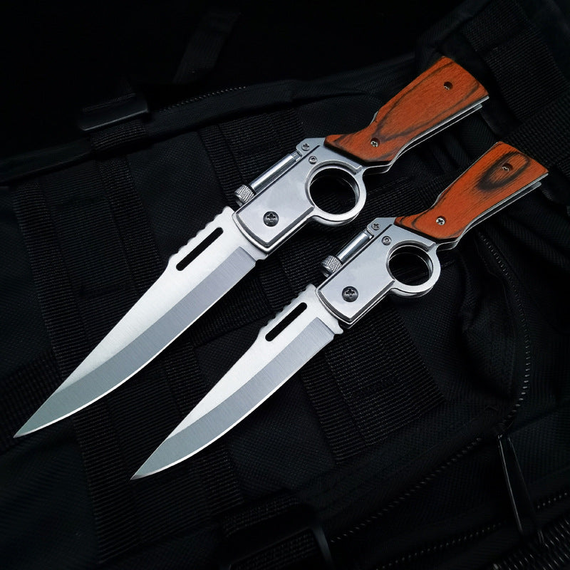 Two open wood-handle folding knives side by side on black tactical fabric