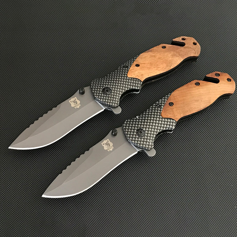 Two open Liome X50 folding knives in parallel showing wooden scales, carbon fiber pattern mid-bodies and sawback blades