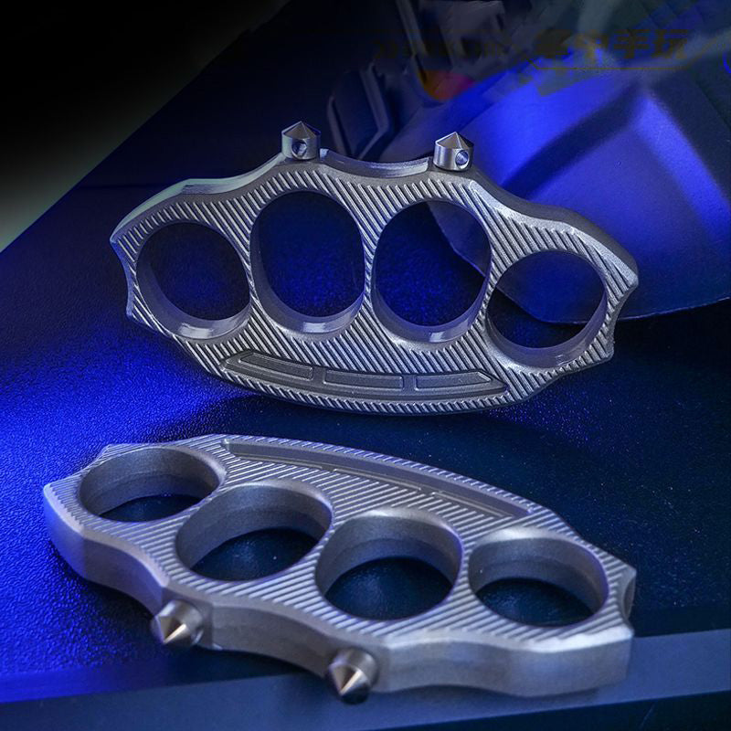 Two zinc-alloy knuckle dusters with four finger holes and detachable window-breaking cones under blue lighting
